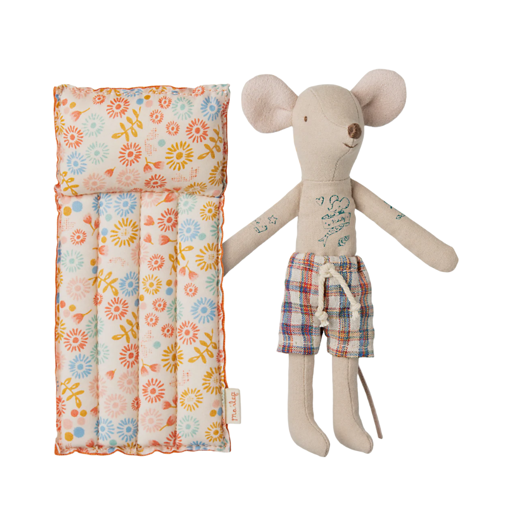 Toy mouse with plaid shorts next to a floral-patterned bag on a white background