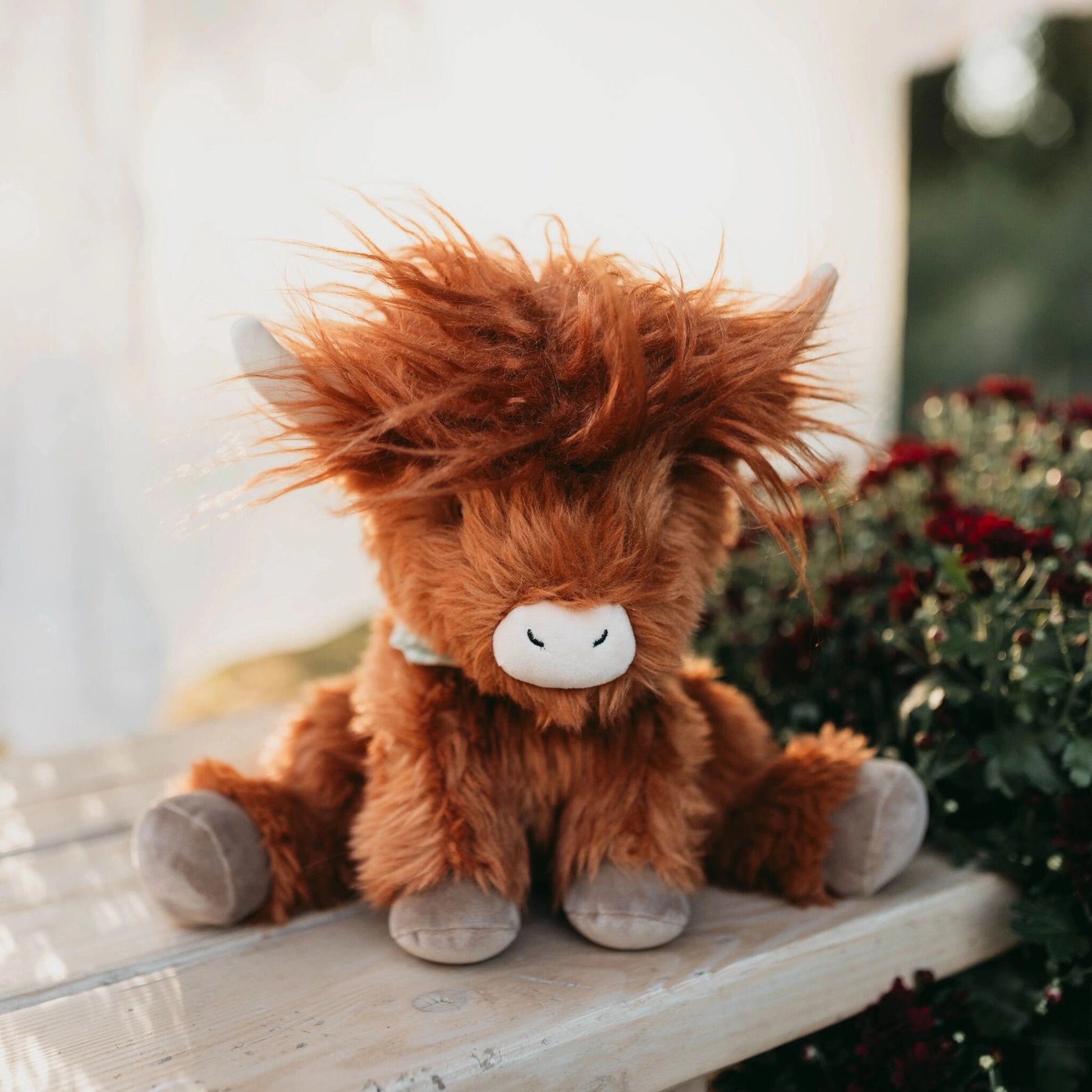 Brown plush toy horse sitting on a wooden surface with a blurred natural background