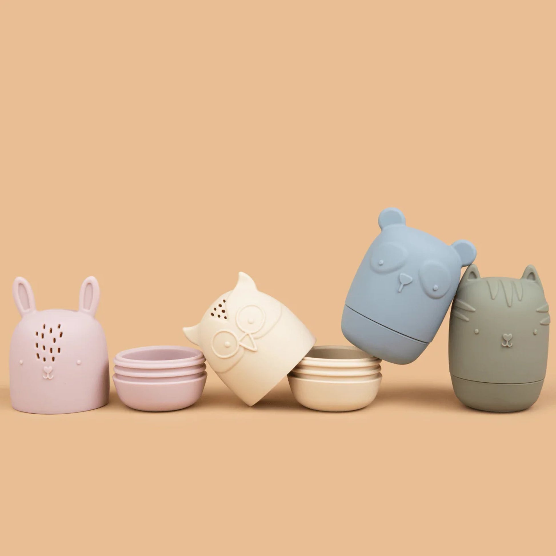 Five animal-shaped containers in pastel colors on a beige background