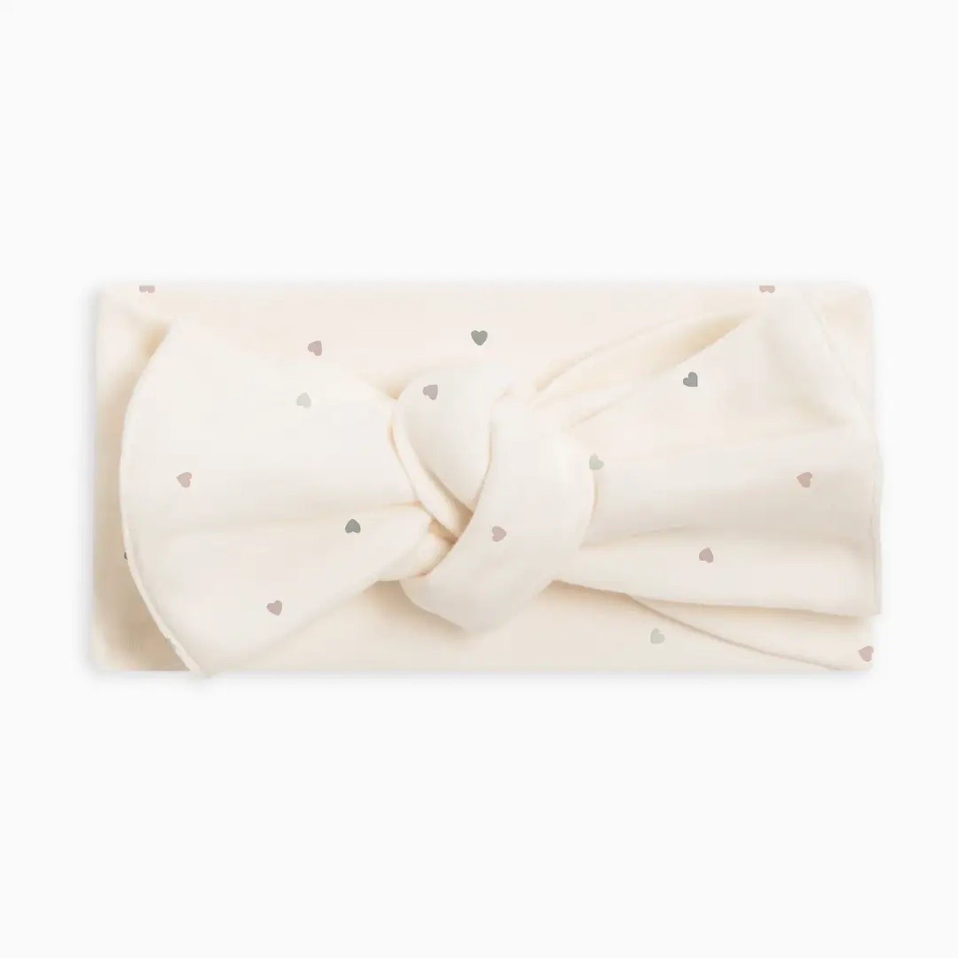 An off-white fabric headband with a large bow and small metallic silver heart details, displayed on a clean white background.
