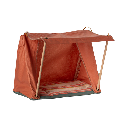 A small orange-brown fabric dog crate or playpen with a hinged flap, supported by two light wood legs and featuring a striped cushion inside, shown on a plain white background.