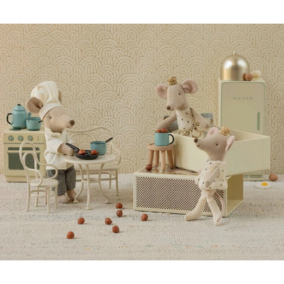 Three toy mice in a staged kitchen setting with a patterned wallpaper background.