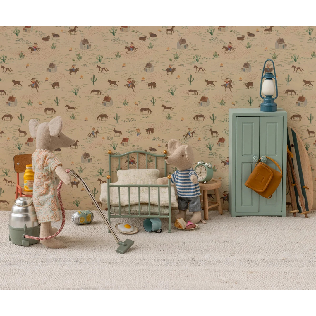 Miniature scene with toy mice in a bedroom setting against a patterned wallpaper.