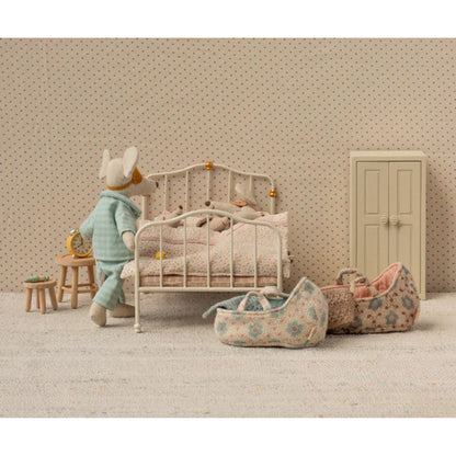 Miniature bedroom scene with a toy mouse, bed, and toys on a neutral background