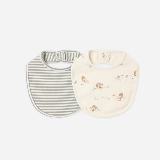 Two baby bibs on a light gray background. One bib is white with thin gray stripes, and the other is cream with small brown animal illustrations.
