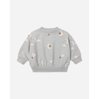 A light gray long-sleeve crewneck sweatshirt for toddlers, featuring an all-over celestial print of white clouds, crescent moons, and small brown stars.