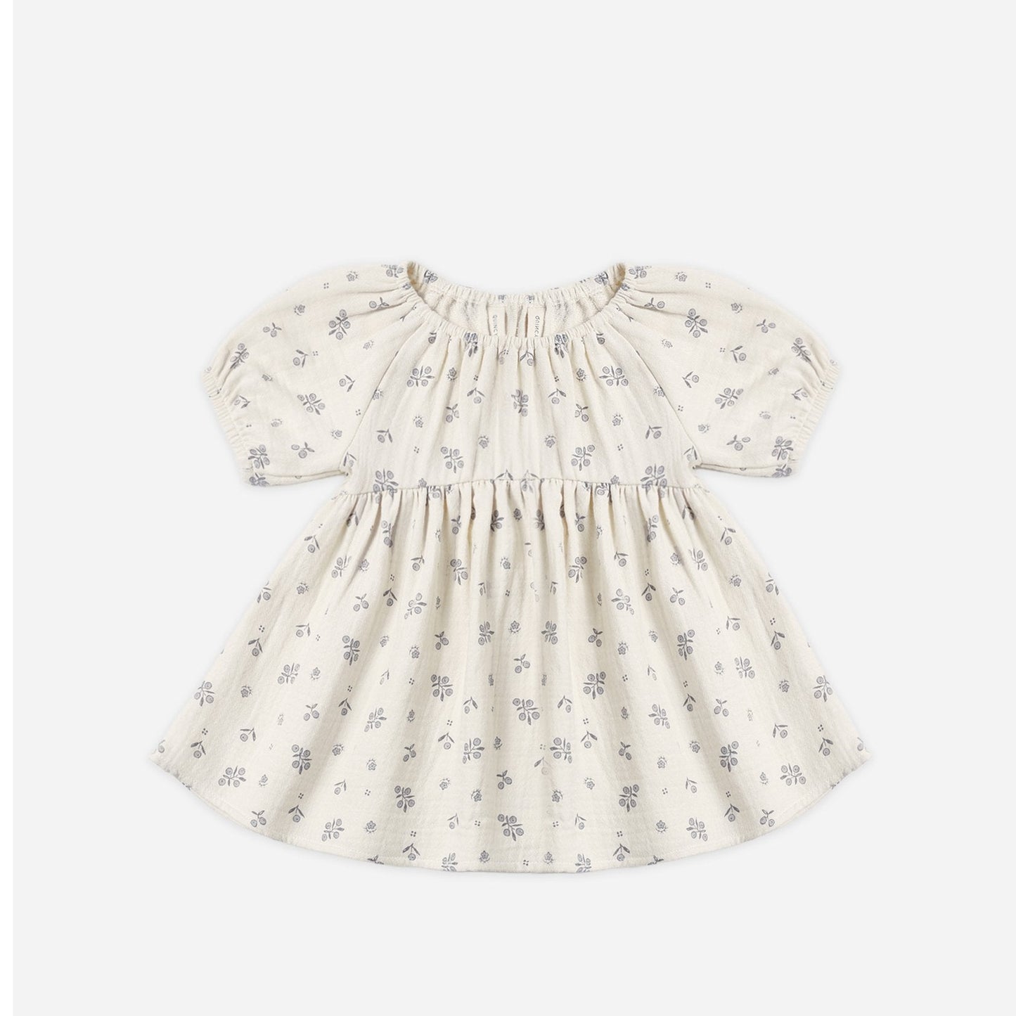A baby girl's short-sleeve dress in cream cotton fabric with a delicate gray floral print, featuring a smocked bodice and puffed sleeves, shown flat on a light gray background.