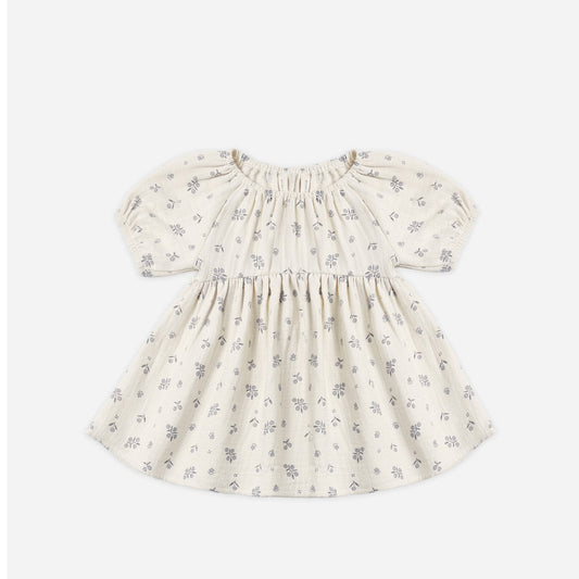 A baby girl's short-sleeve dress in cream cotton fabric with a delicate gray floral print, featuring a smocked bodice and puffed sleeves, shown flat on a light gray background.