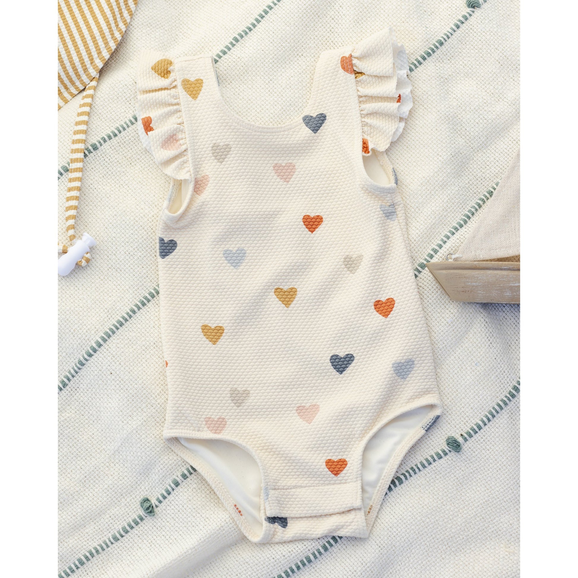 Baby onesie with heart pattern on a textured surface