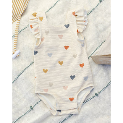 Baby onesie with heart pattern on a textured surface