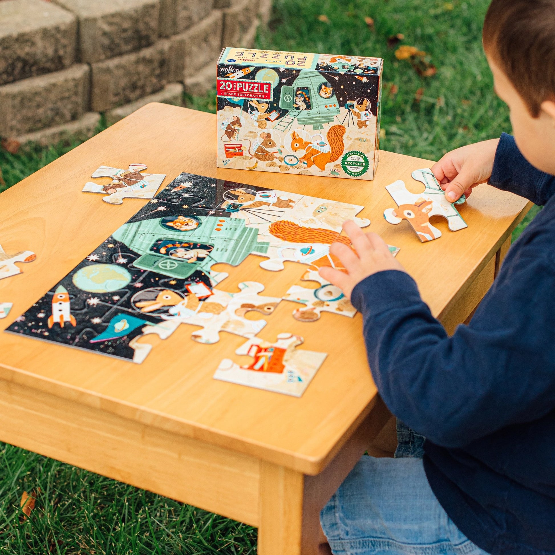 Child playing with a puzzle on a wooden table outdoors