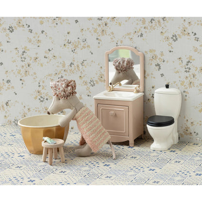 Children's bathroom set with toy mouse, bathtub, sink, and toilet against a floral wallpaper background.