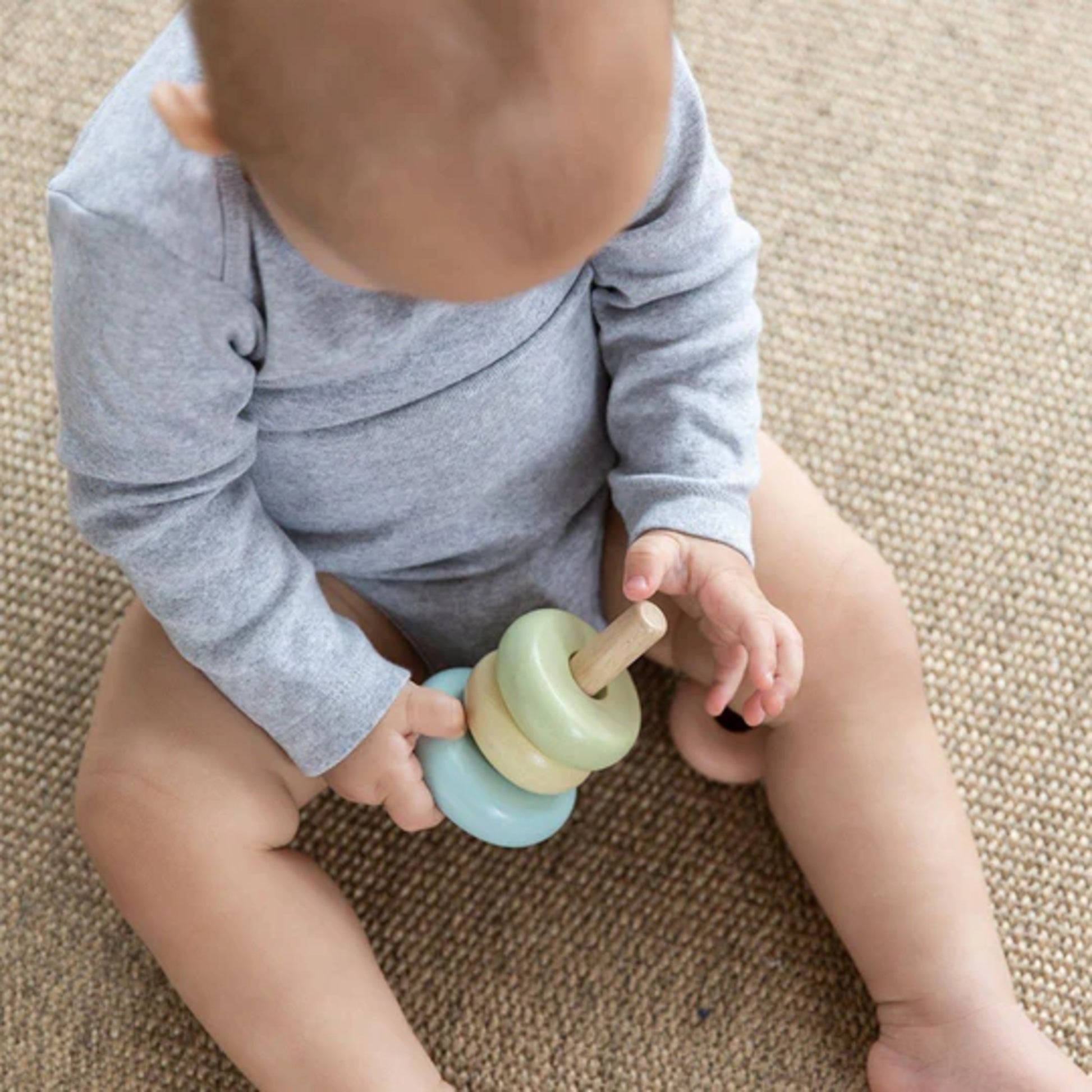 Baby playing with a colorful toy on a carpeted floor