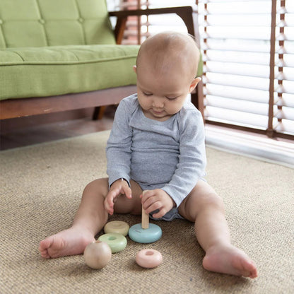 Baby playing with wooden toys on a carpeted floor.